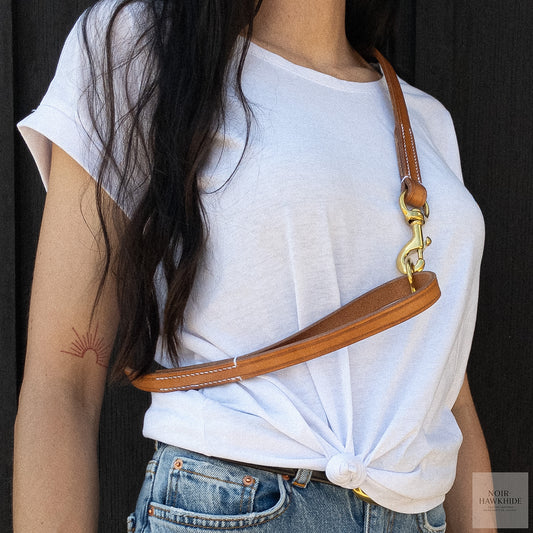 Handmade leather dog leash worn over the shoulder for hands-free carrying.