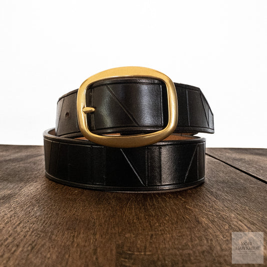 Handcrafted black leather belt with geometric hand-tooled pattern shown in full length.