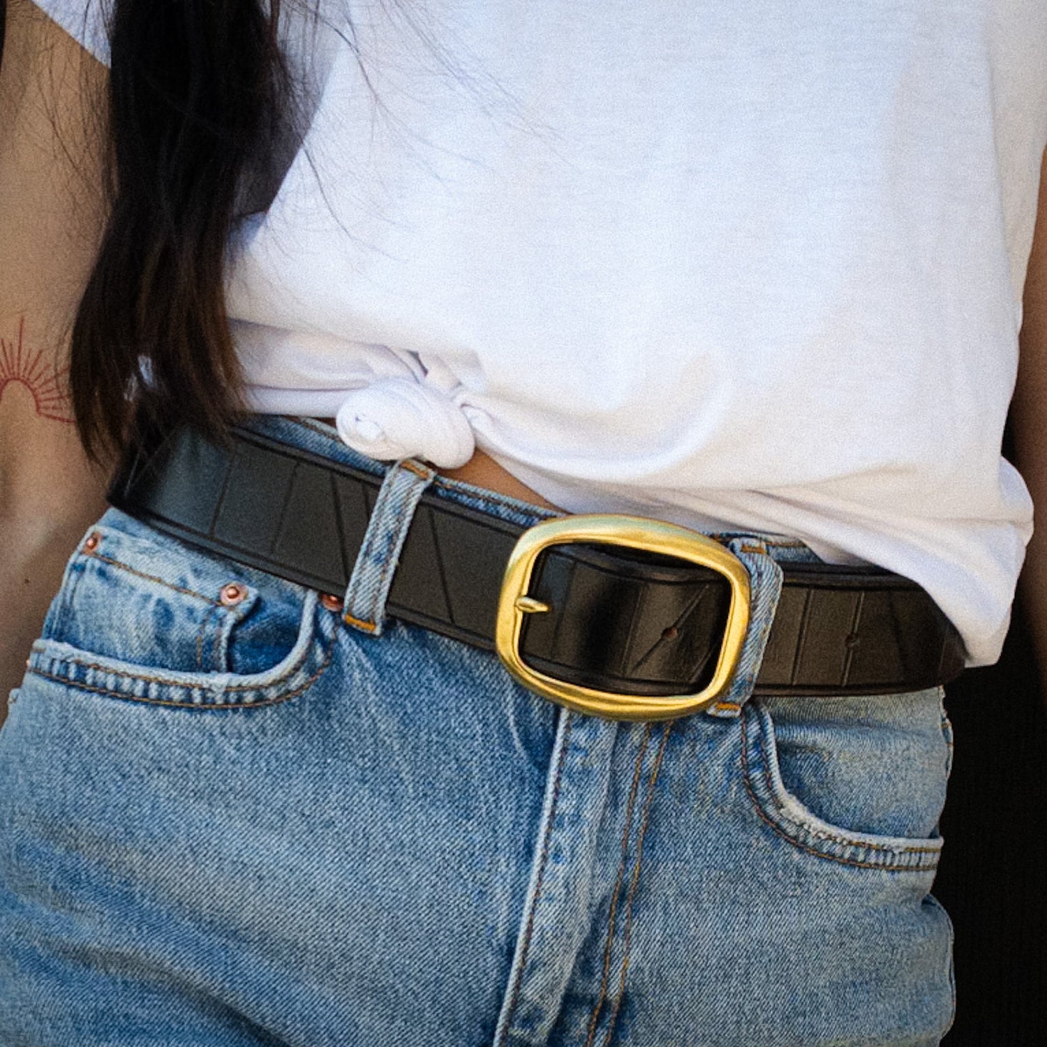 Black handcrafted leather belt worn with blue denim jeans.