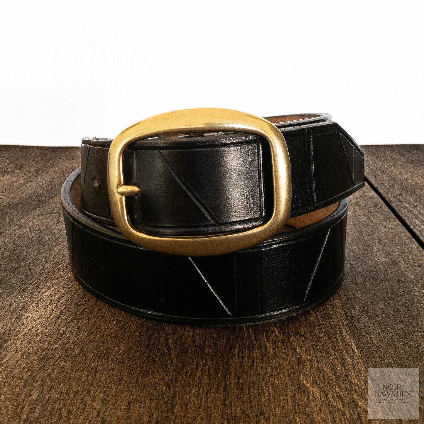 Detail shot of a solid brass buckle on a handcrafted black leather belt.