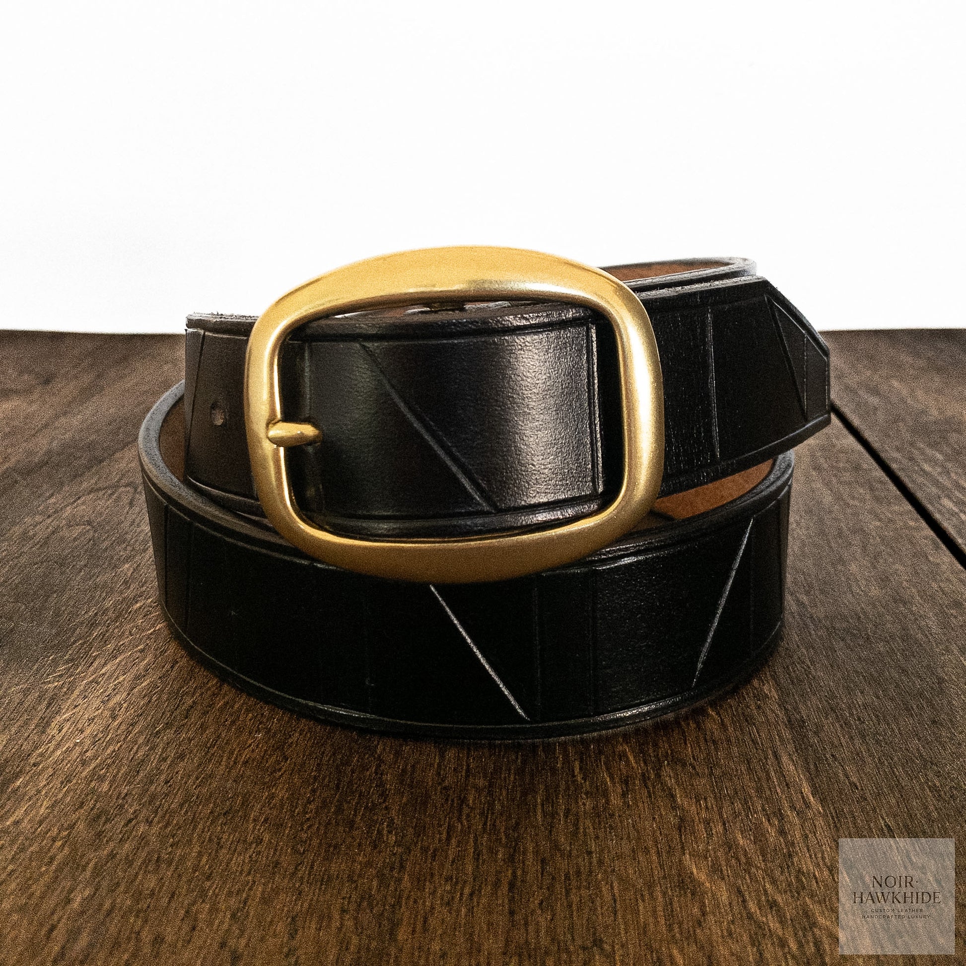 Detail shot of a solid brass buckle on a handcrafted black leather belt.