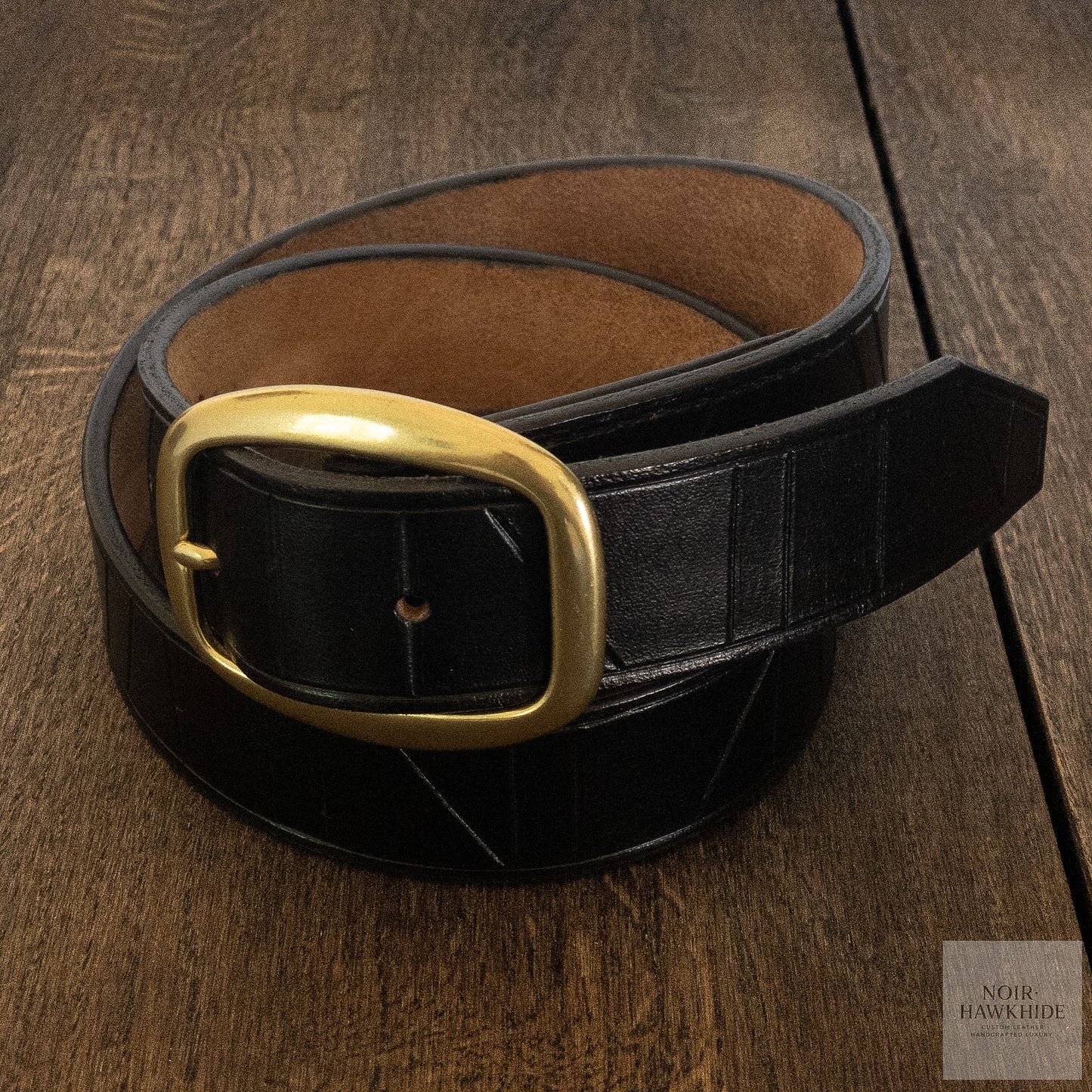 Handcrafted black leather belt photographed from the front with solid brass buckle.