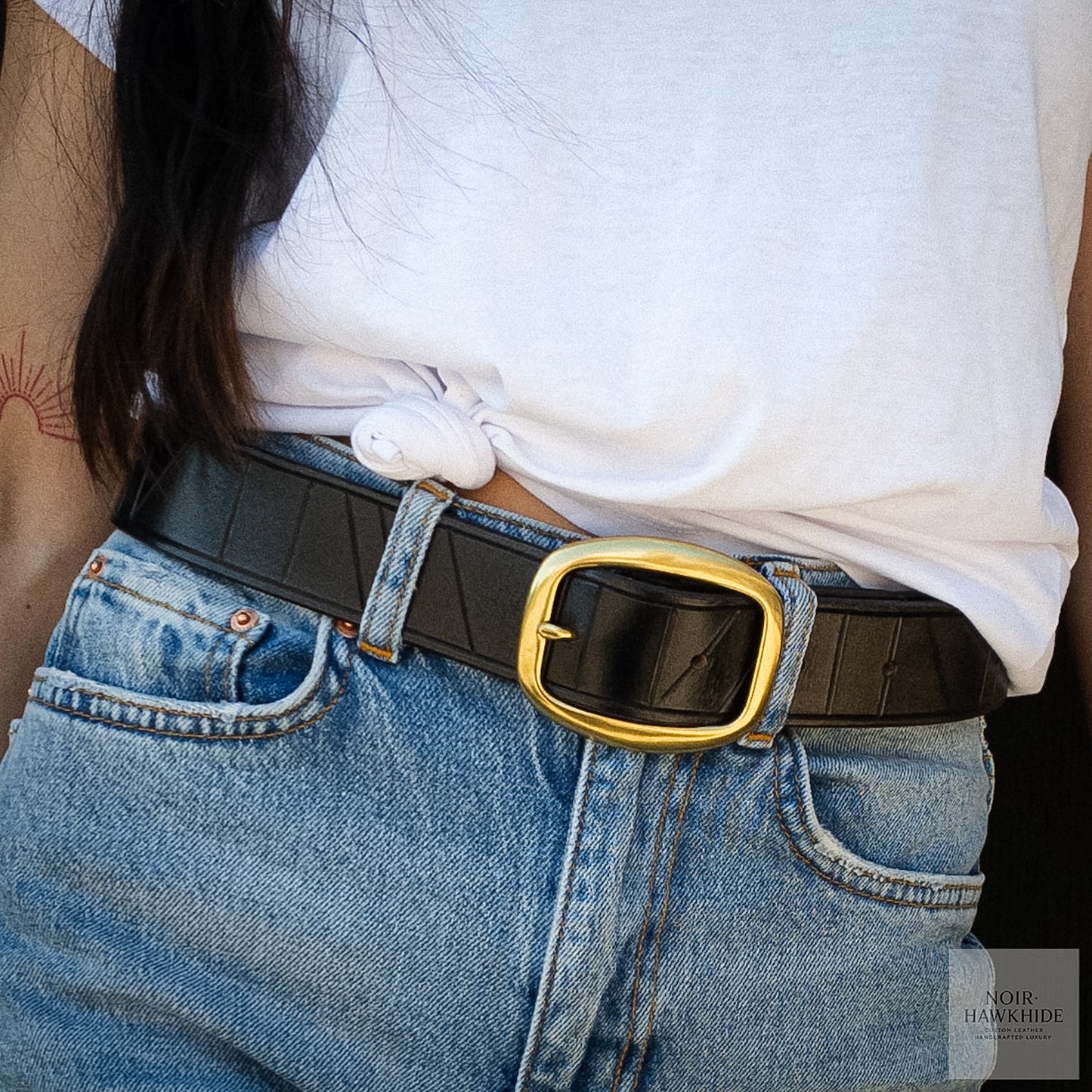 Handcrafted black leather belt styled with blue jeans and a white t-shirt.