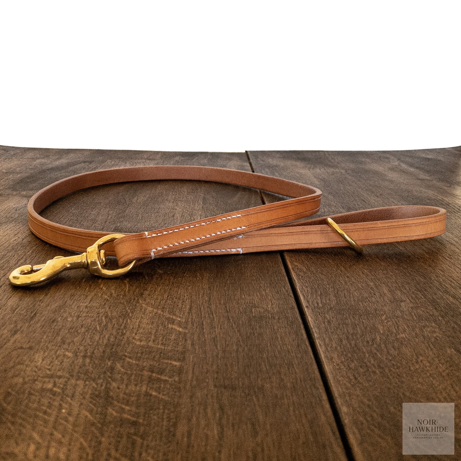 Handmade leather dog leash laid flat showing solid brass hardware and hand stitching.