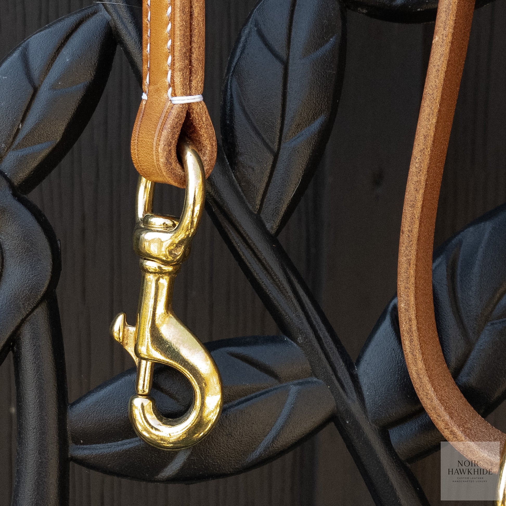 Close-up of solid brass snap hook on handmade leather dog leash.